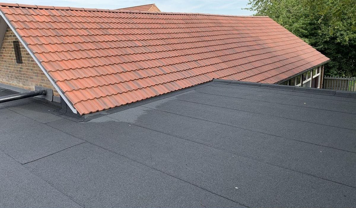 Dark felt flat roof alongside a terracotta tiled roof