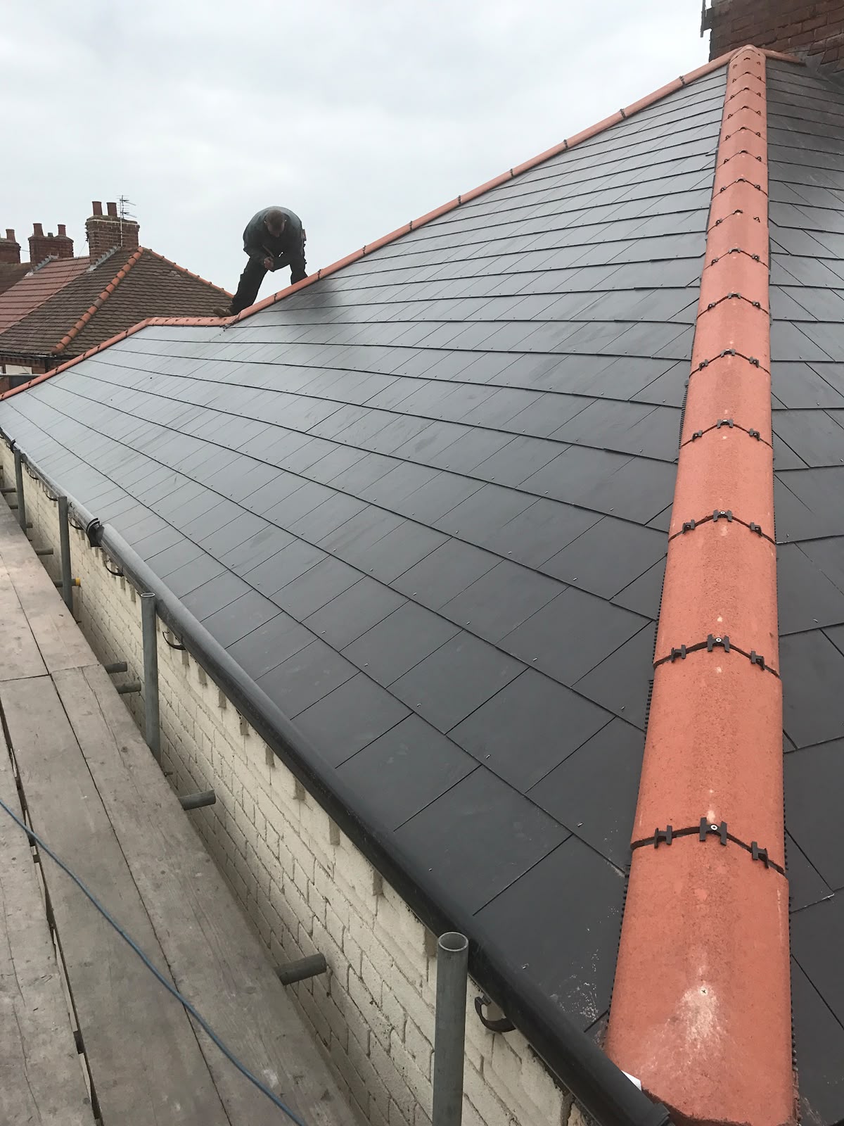 Slate-coloured roof with terracotta dry ridge and hip tiles