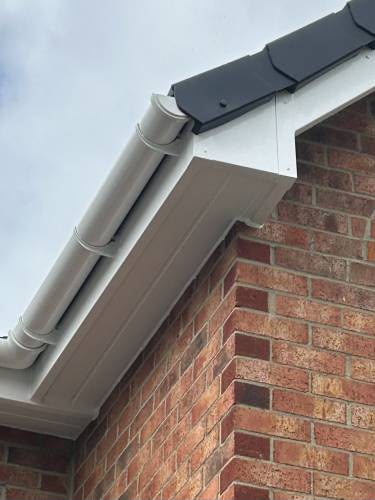 White gutter fascia and soffit at the corner of a brick house